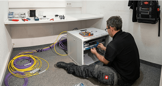 Techniker bei der Montage eines Netzwerkschranks mit Glasfaserverkabelung